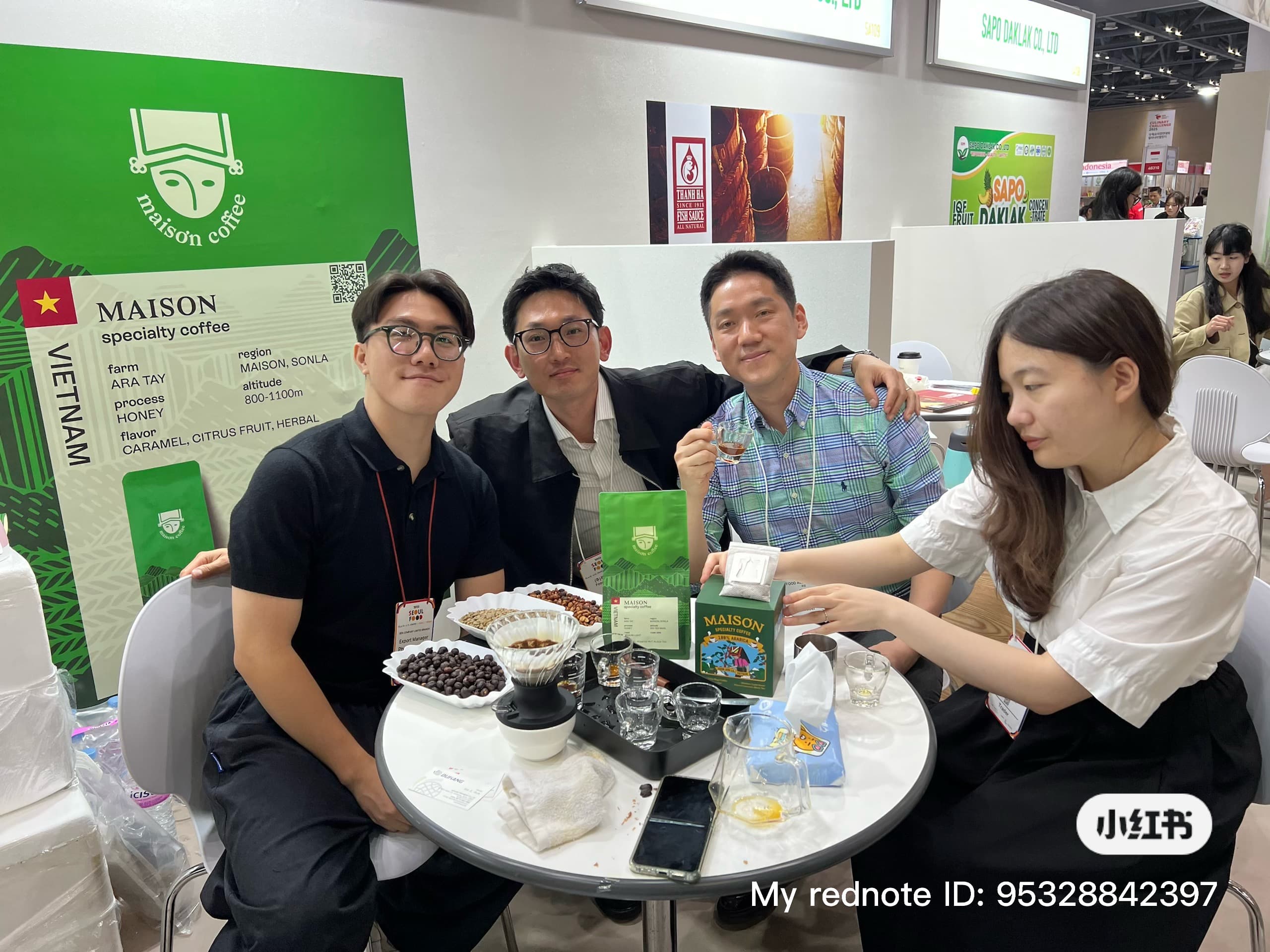 Đội ngũ Maison Coffee tại một hội chợ quốc tế, cùng bộ dụng cụ cupping và thẻ thông số nông trại